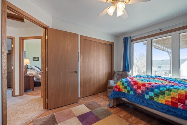 bedroom with a closet, carpet floors, ceiling fan, and wood finished floors