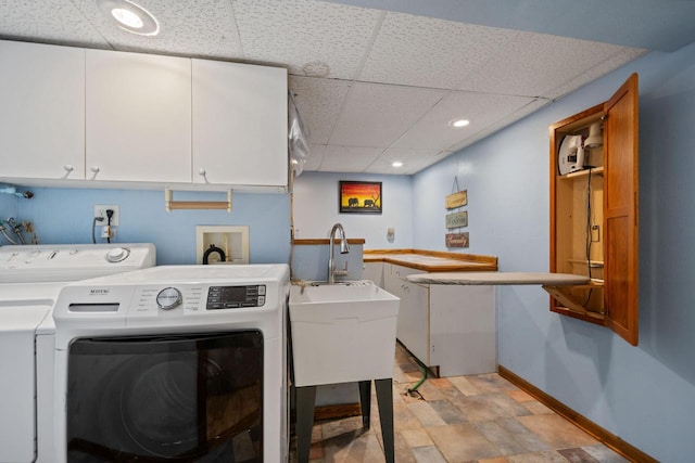 clothes washing area featuring baseboards, recessed lighting, cabinet space, a sink, and washing machine and dryer