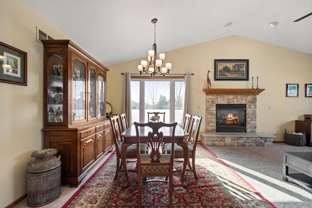 dining area with visible vents, a stone fireplace, carpet flooring, a chandelier, and vaulted ceiling