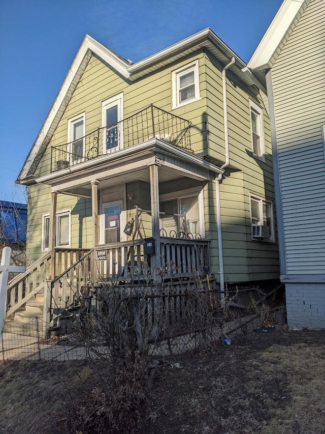 view of front of house featuring a porch, fence, and a balcony