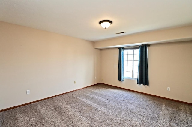 spare room with carpet flooring, visible vents, and baseboards