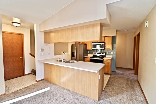 kitchen featuring lofted ceiling, appliances with stainless steel finishes, carpet flooring, a sink, and a peninsula