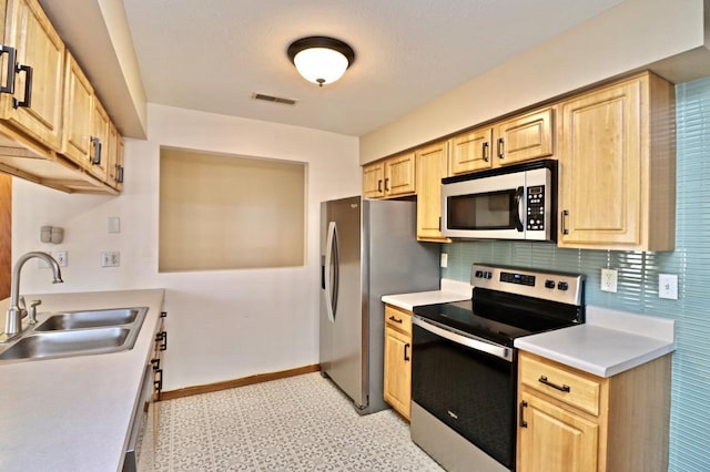 kitchen featuring light brown cabinets, appliances with stainless steel finishes, and a sink