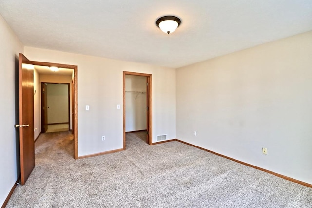 unfurnished bedroom with visible vents, baseboards, a closet, carpet, and a walk in closet