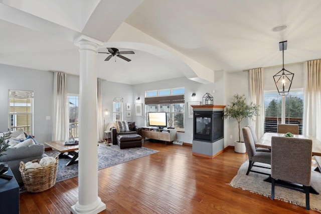 living area featuring wood-type flooring, a healthy amount of sunlight, and ornate columns