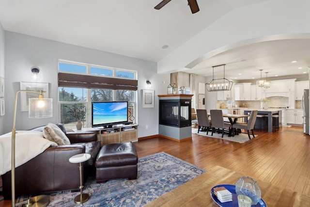 living area with a ceiling fan, baseboards, recessed lighting, arched walkways, and dark wood-style flooring