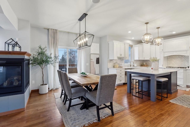 dining room featuring recessed lighting, a multi sided fireplace, an inviting chandelier, and hardwood / wood-style flooring