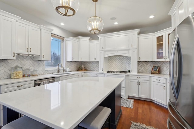 kitchen with a sink, a kitchen breakfast bar, appliances with stainless steel finishes, and white cabinets