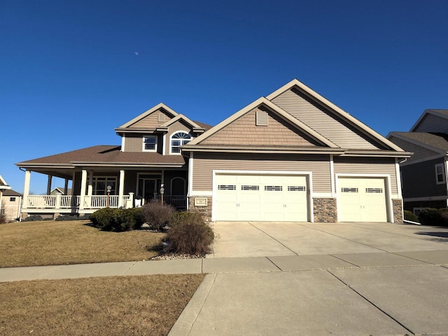 craftsman-style home with concrete driveway, an attached garage, covered porch, and stone siding