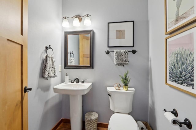 half bath with baseboards and toilet