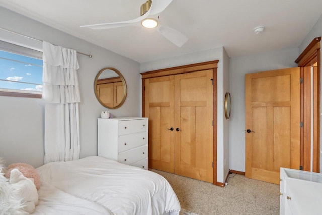 bedroom with light carpet, ceiling fan, baseboards, and a closet