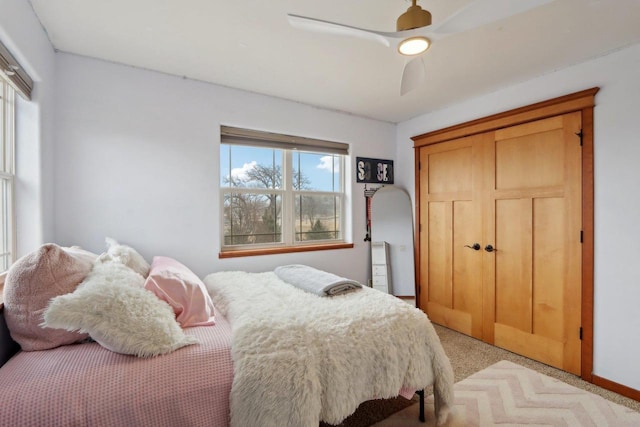 bedroom with light colored carpet, a ceiling fan, and a closet