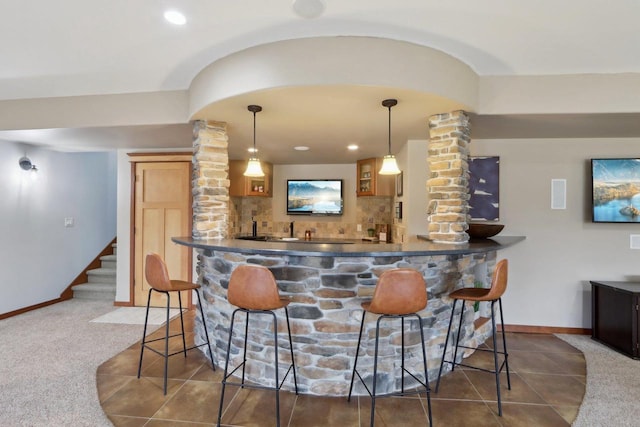 bar with stairway, ornate columns, indoor wet bar, carpet flooring, and tasteful backsplash