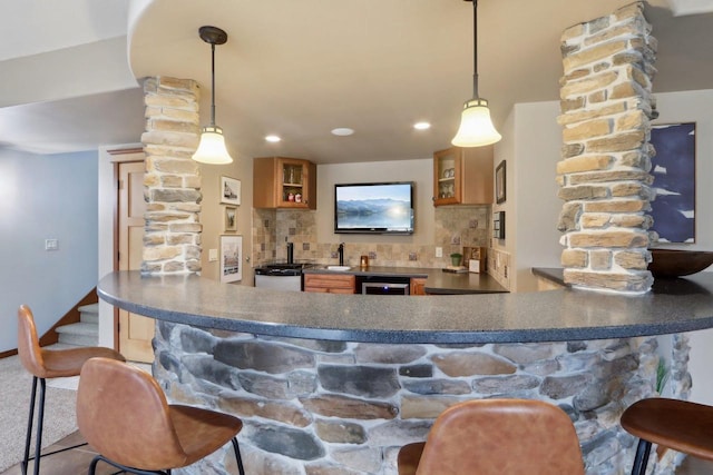 bar with indoor wet bar, backsplash, beverage cooler, and decorative columns