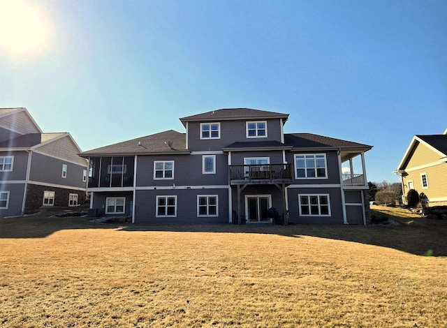 back of house featuring a yard, a balcony, and a sunroom