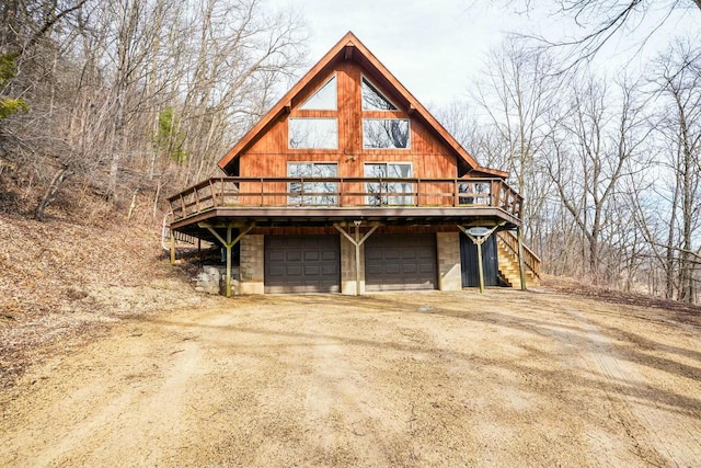 view of home's exterior with an attached garage, dirt driveway, and stairs