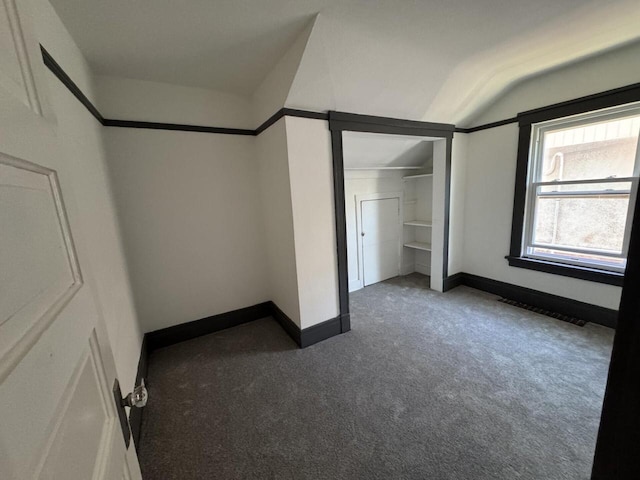 unfurnished bedroom with lofted ceiling, a closet, carpet, and baseboards