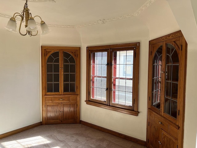 unfurnished dining area with a chandelier, carpet floors, and baseboards