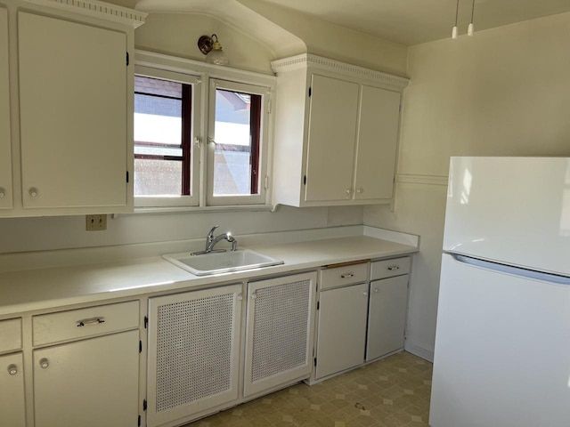 kitchen featuring freestanding refrigerator, light countertops, a sink, and light floors