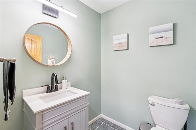 half bathroom with toilet, baseboards, and vanity