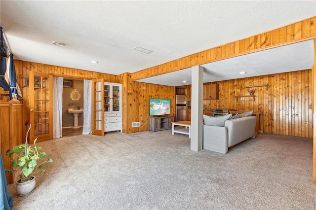 unfurnished living room featuring carpet floors, visible vents, and wooden walls