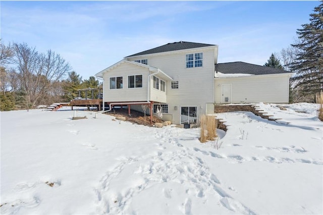 snow covered house featuring a deck, stairway, and a garage