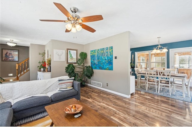 living area featuring visible vents, stairway, ceiling fan, wood finished floors, and baseboards