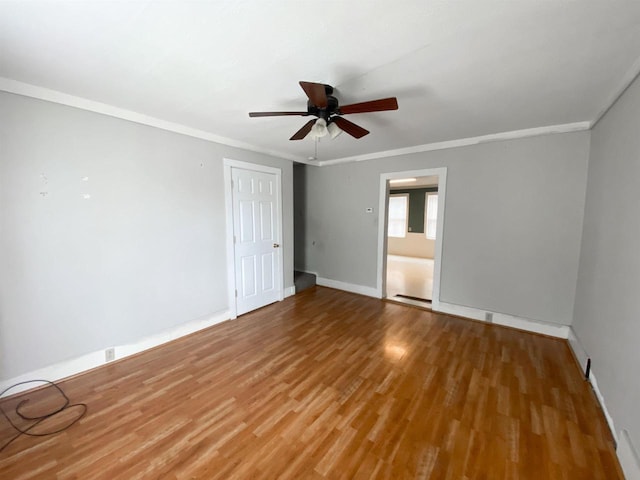 unfurnished room featuring ornamental molding, wood finished floors, a ceiling fan, and baseboards