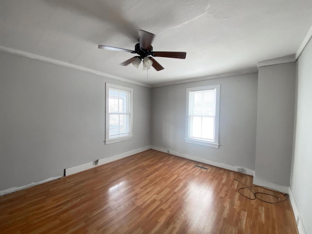 unfurnished room with a wealth of natural light, crown molding, and wood finished floors