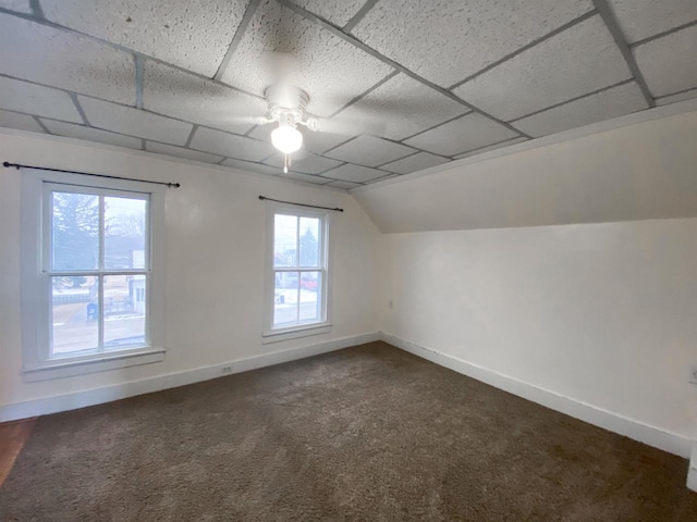 bonus room with dark colored carpet, vaulted ceiling, baseboards, and ceiling fan