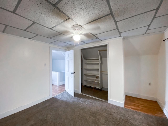 unfurnished bedroom with a closet, carpet flooring, a paneled ceiling, and baseboards