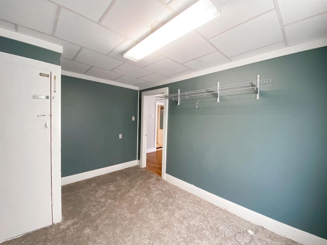 carpeted spare room with baseboards and a drop ceiling