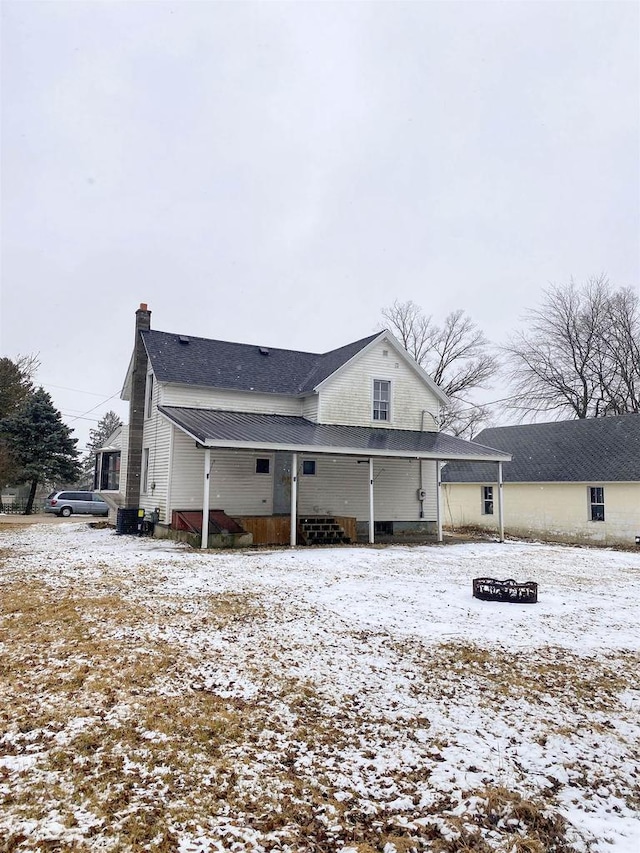 snow covered back of property with a chimney