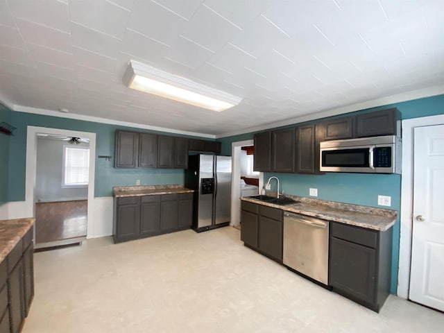 kitchen featuring appliances with stainless steel finishes, a sink, dark brown cabinetry, and a ceiling fan