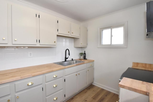 kitchen featuring a sink, backsplash, baseboards, light wood-style floors, and wooden counters