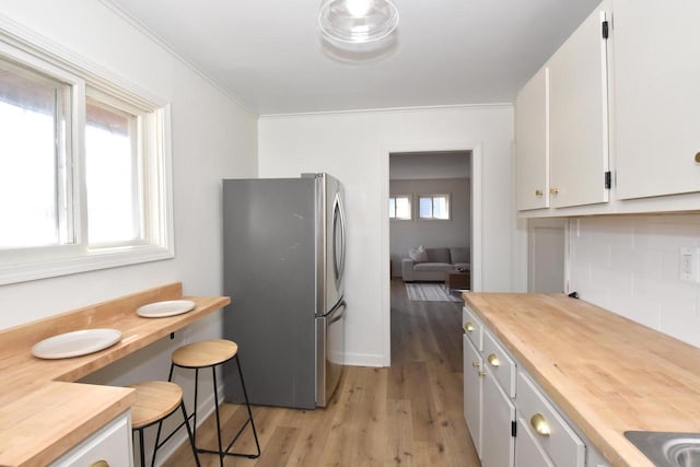 kitchen featuring freestanding refrigerator, wood counters, white cabinetry, tasteful backsplash, and light wood-type flooring