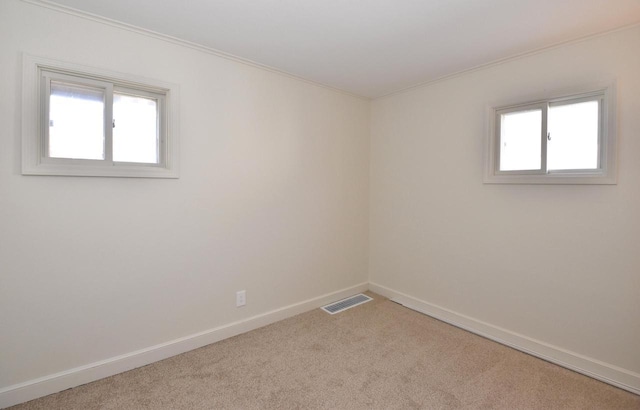 empty room featuring carpet, visible vents, and a wealth of natural light