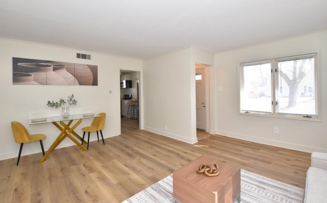 living room with light wood-type flooring, visible vents, and baseboards