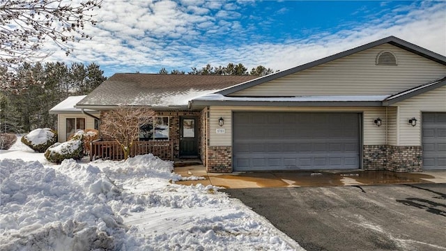 ranch-style home featuring a garage, brick siding, and driveway