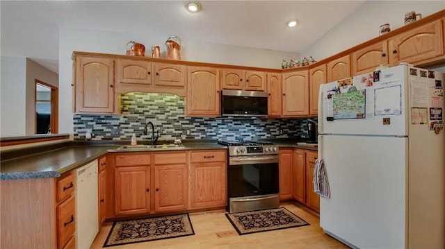 kitchen with stainless steel appliances, backsplash, dark countertops, and a sink