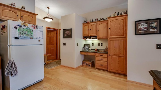 kitchen with lofted ceiling, light wood-type flooring, built in study area, freestanding refrigerator, and dark countertops