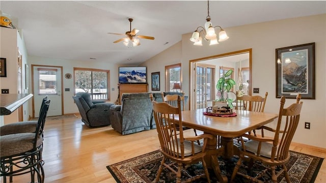 dining area with light wood-type flooring, ceiling fan with notable chandelier, and lofted ceiling