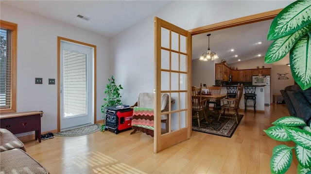 interior space featuring light wood-style floors, visible vents, vaulted ceiling, and a notable chandelier