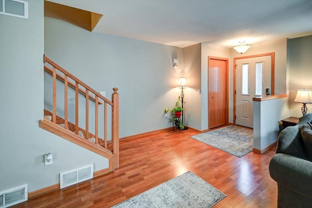 foyer with stairway, wood finished floors, visible vents, and baseboards