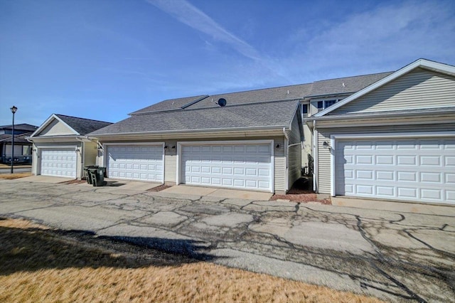 view of front of house featuring community garages and a shingled roof