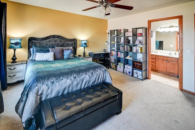 bedroom with ceiling fan, light colored carpet, ensuite bath, and a sink