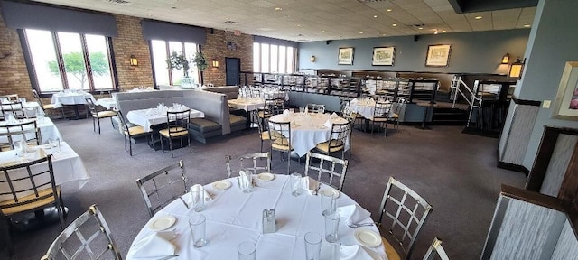 dining area with visible vents, plenty of natural light, and brick wall