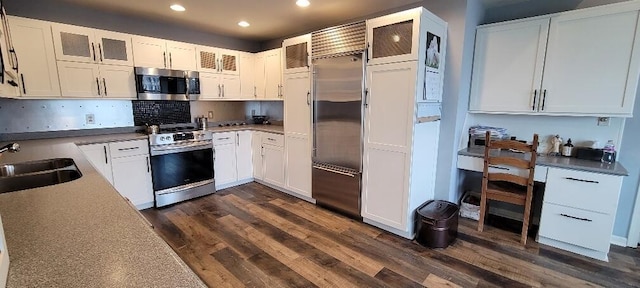 kitchen with a sink, appliances with stainless steel finishes, white cabinets, and dark wood-style flooring