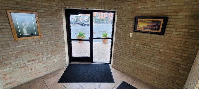 entryway with brick wall and light tile patterned floors