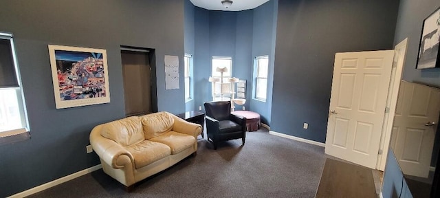 living area with carpet, a towering ceiling, and baseboards